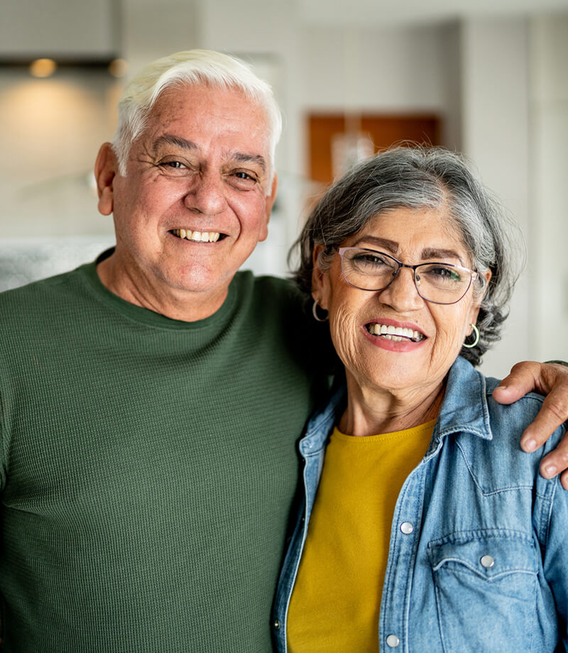 Smiling older couple standing close together indoors.